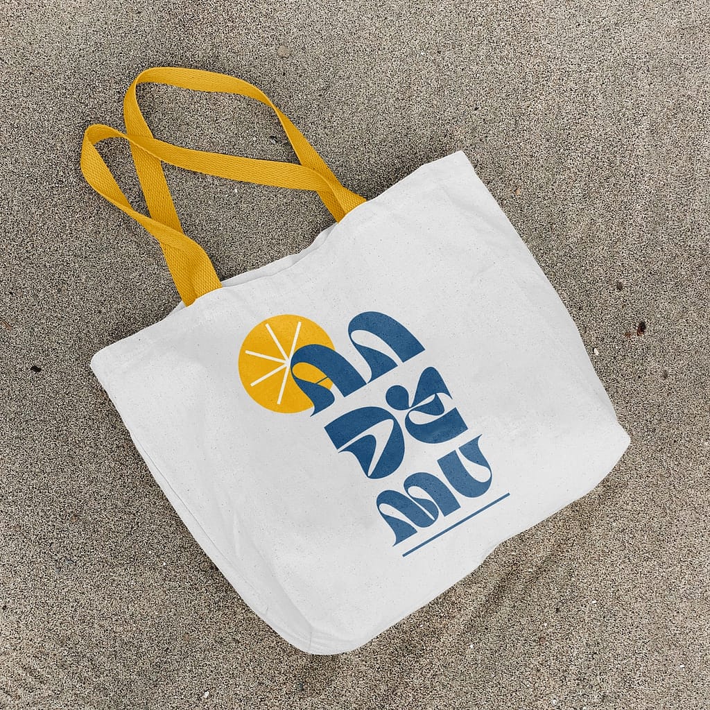 Photo d'un sac de plage en tissu posé sur le sable avec le logo d'un bar de dessus